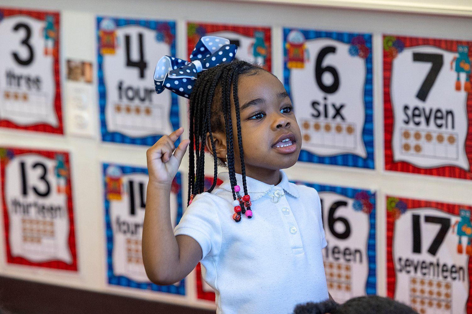 Diverse student in a classroom raising hand to answer a question